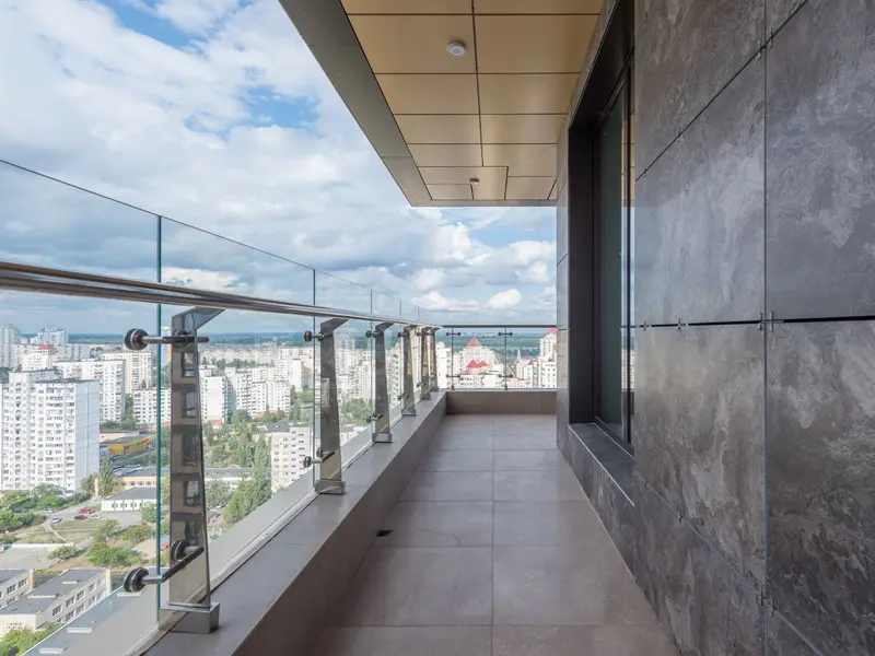 Dug balkon sa staklenom ogradom i inox rukohvatom, pogled na grad